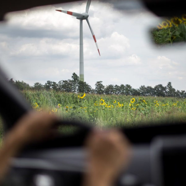 Blick durch Windschutzscheibe auf Windrad und Wiese